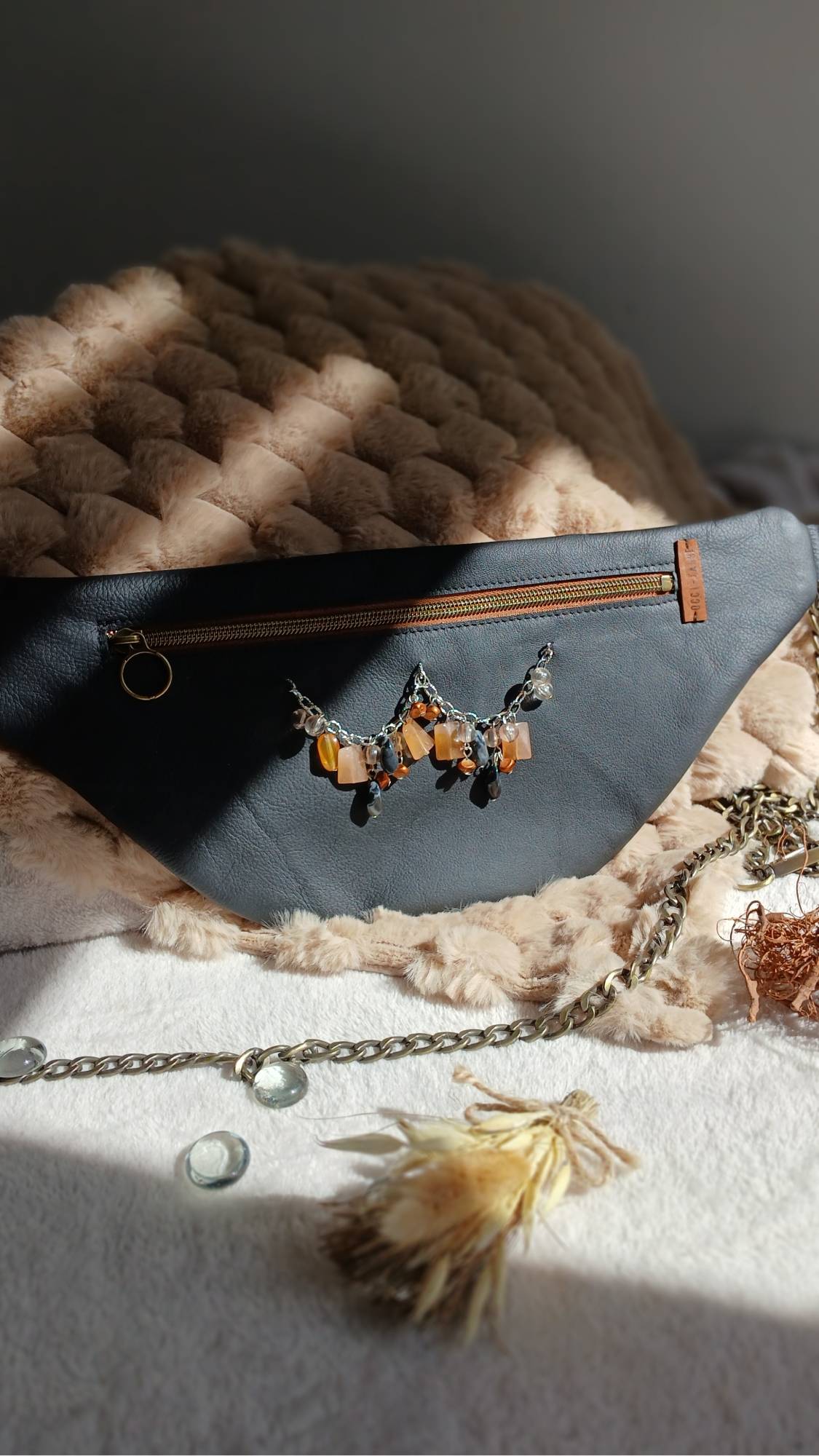 Vue de face du sac banane Sépia, en cuir surcyclé noir. Avec son collier de seconde main au style ethnique, il est un accessoire élégant, féminin et singulier, fait main.