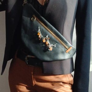 Vue portée de près du sac banane Sépia, en cuir surcyclé. Avec son collier de seconde main au style ethnique, il est un accessoire élégant, féminin et singulier, fait main.