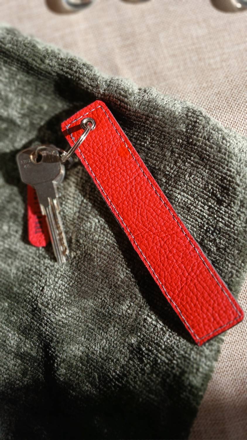 Vue arrière du porte-clés Coq'Uette en cuir surcyclé rouge et noir. Il reprend une chute de cuir à motif coq et un cuir rouge ciré. Il fait partie de la catégorie les Complices « Coq'Uette ». C'est un accessoire féminin, unique, affirmé, fait main.