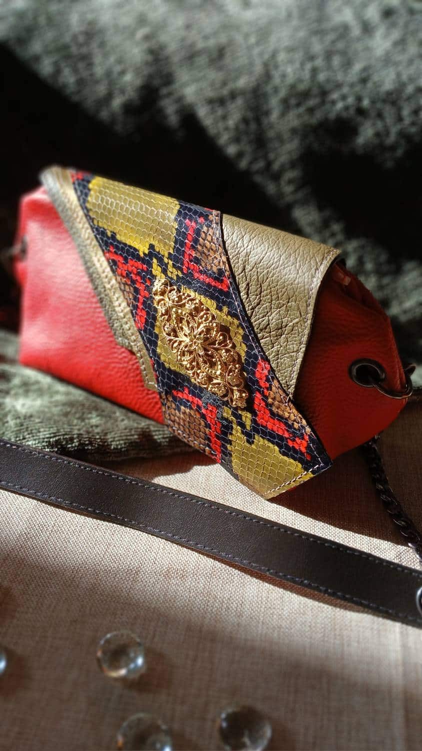 Vue de biais du sac Serpentine en cuir surcyclé rouge et motif serpent. C'est un accessoire féminin, élégant, affirmé, fait main.