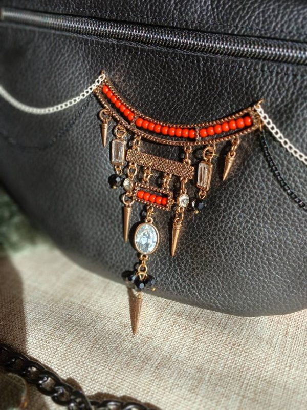 Vue sur le bijou du sac banane Flamenca en cuir upcyclé noir et rouge, fait main. Avec ses tons contrastés et son collier de seconde main assorti, féminité assumée. Une création artisanale et unique.